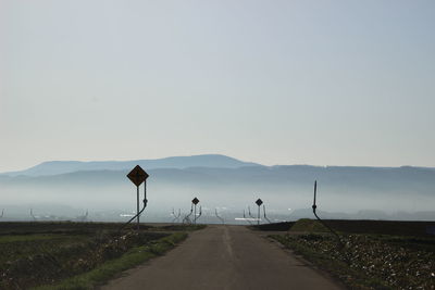 Road leading towards mountains against clear sky