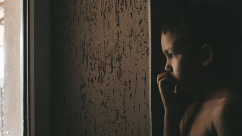 Boy looking through window at home