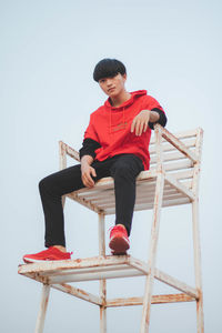 Full length of boy looking at sitting against clear sky