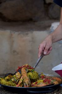 Midsection of person serving paella