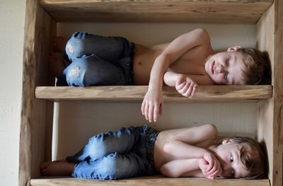 Siblings sleeping in cabinet at home