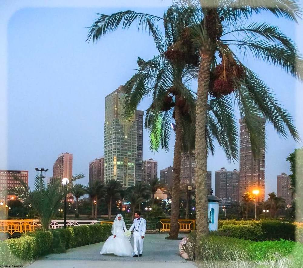 PEOPLE AT PARK BY CITY AGAINST SKY