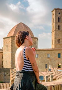 Woman sitting against buildings in city