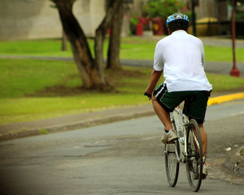 Rear view of man riding bicycle on road