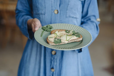 Midsection of female owner holding bruschetta while standing in cafe