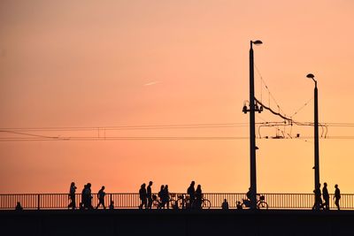 Silhouette people on bridge against sky during sunset