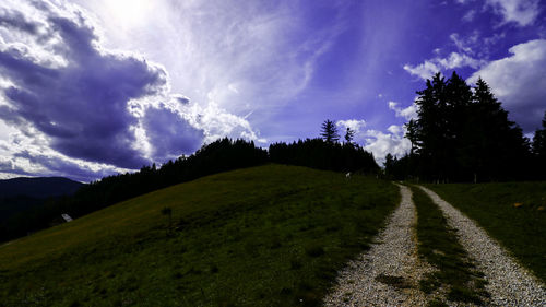 Panoramic view of road amidst field against sky