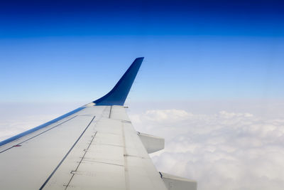 Airplane flying over clouds against blue sky