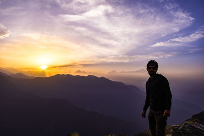 Portrait of man standing on mountain against sky during sunset
