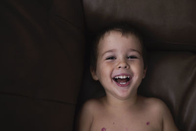 Portrait of smiling boy lying on sofa