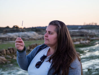 Portrait of woman looking at camera against sky during sunset