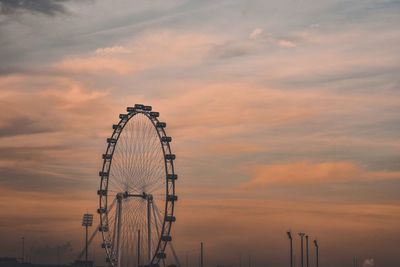 Low angle view of ferris wheel against cloudy sky