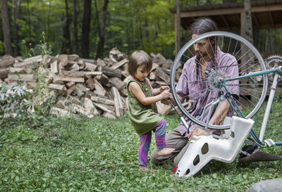 Man looking at daughter pumping bicycle tier in backyard