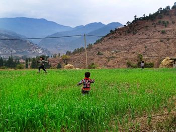 People on field by mountain against sky