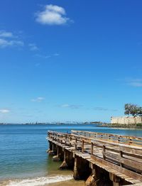 Pier over sea against blue sky