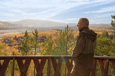 Rear view of woman standing on railing against sky