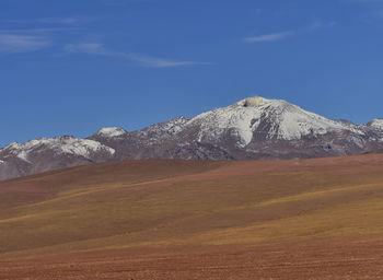 Scenic view of snowcapped volcano against blue sky