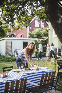 Mature woman arranging food on table in backyard during weekend