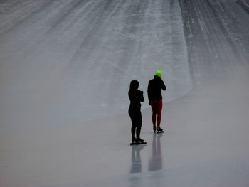 Rear view of women standing on ice rink