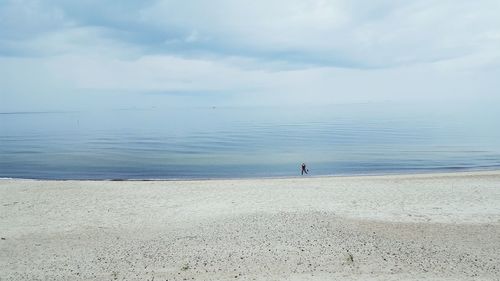 Woman on shore at beach against sky