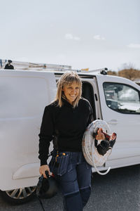 Smiling female worker carrying equipment outdoors