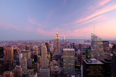 Modern buildings in city against sky during sunset