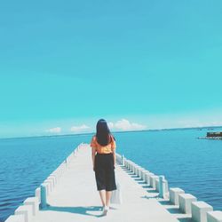 Rear view of woman looking at sea against clear sky