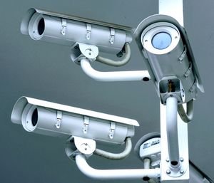 Low angle view of security cameras against gray background