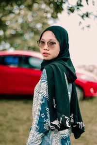 Portrait of young woman wearing sunglasses standing outdoors