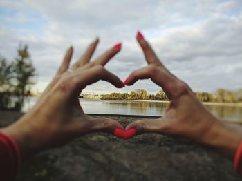 Close-up of hands holding heart shape against sky