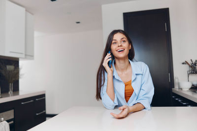 Portrait of young woman using mobile phone at home