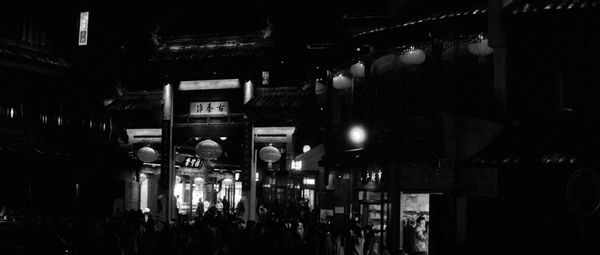 People on illuminated street in city at night