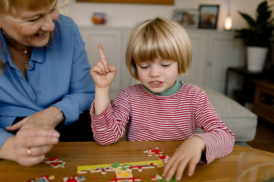 Boy playing jigsaw puzzle with grandmother at home