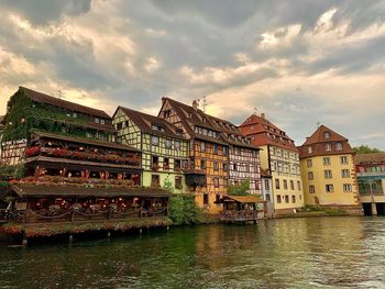 Buildings by river against sky
