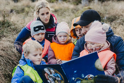 Playschool teachers reading book to children during walk