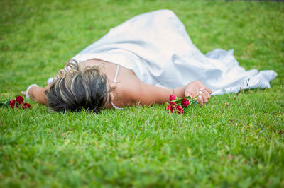 Midsection of woman lying on grassy field