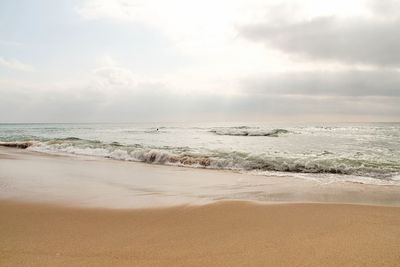 Scenic view of beach against cloudy sky