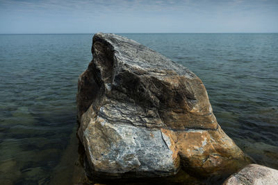 Rock formation in sea against sky
