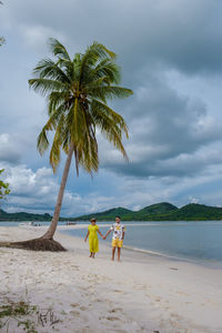 Rear view of woman walking at beach against sky