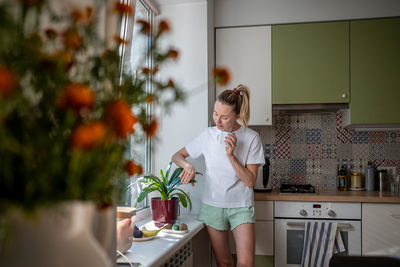 Portrait of young woman standing against wall