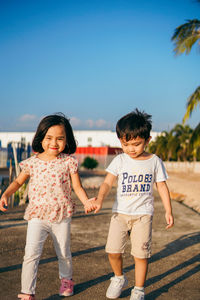 Full length of siblings holding hands walking on street