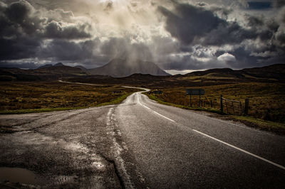 Road amidst field against sky