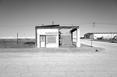 Empty road by building against clear sky