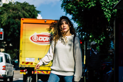 Portrait of young woman standing against bus