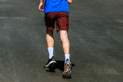 Low section of man skateboarding on road