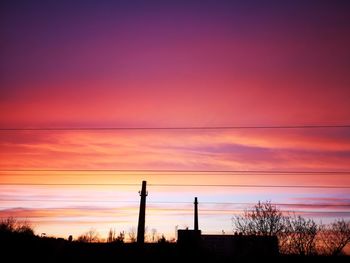 Silhouette trees against orange sky at sunset