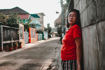 Portrait of young woman standing against wall