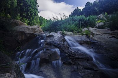 Scenic view of waterfall against sky