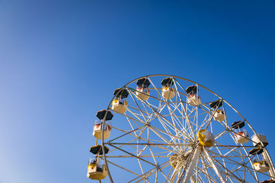 Low angle view of ferris wheel against clear blue sky