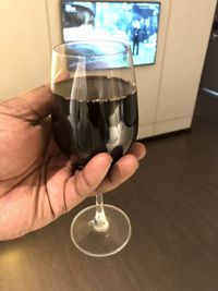 Close-up of hand holding wine glass on table